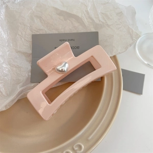 Detailed view of large matte pink rectangle hair claw clip with a silver heart ornament