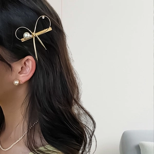 Elegant gold metal bow hair clip with pearls and rhinestones on model's side hair