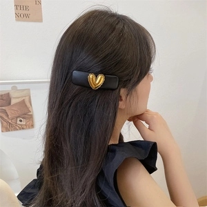 Close-up of a rectangular PU leather BB hair clip with a vintage gold heart charm on a model