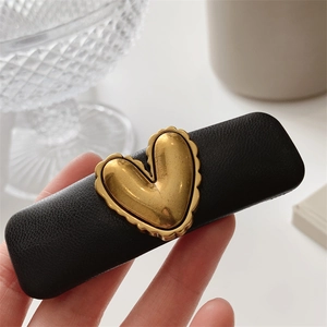 Detail of vintage black leather hair clip with a matte gold heart-shaped metallic ornament