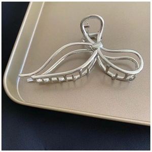 Elegant silver metal shark hair claw with ribbon bow design on a black texture