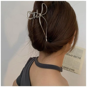 Elegant silver metal bow shark clip for thick hair shown on a minimalist model back view