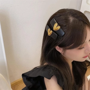 Set of two black PU leather hair clips featuring elegant 3D gold heart metal accents