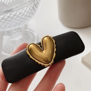 Retro black PU leather sponge hair clip with a gold heart metal accent on glass background