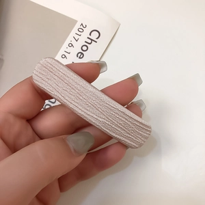 Détail d'une pince à cheveux rose montrant le ruban côtelé et le support métal
