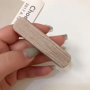 Détail de la texture satinée champagne sur une barrette à cheveux fine de style français