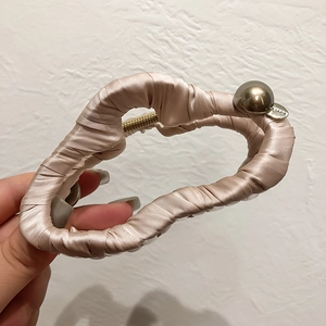 Détail d'une grande pince à cheveux en satin champagne avec perle dorée décorative