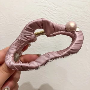 Détail de la pince à cheveux en satin rose avec perle et ressort en métal doré robuste
