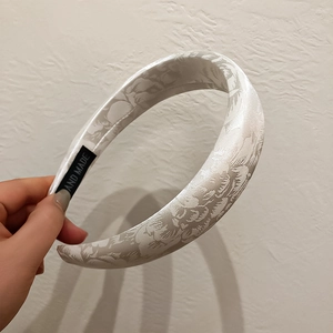 Close-up of white jacquard headband showing floral texture and handmade label