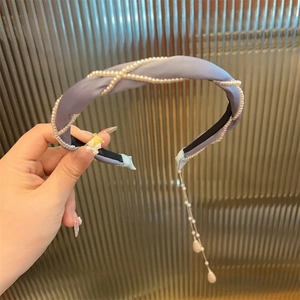 Detail eines lila Stoffstirnbands mit Perlennetz und langen Quasten mit Perlenanhänger