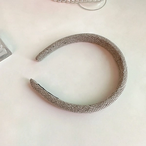 Close-up of champagne gold braided headband with glitter finish and black non-slip lining