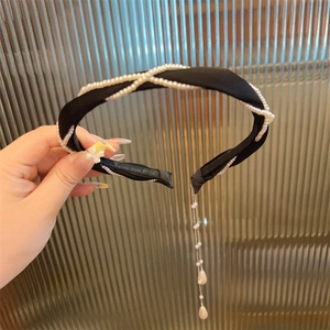 Detail eines schwarzen Satin-Haarreifs mit gekreuzten Perlen und hängenden Ketten