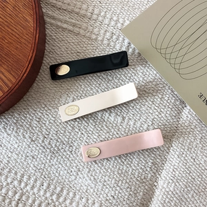 Detailed macro view of three minimalist resin hair clips in black, white, and pink finishes