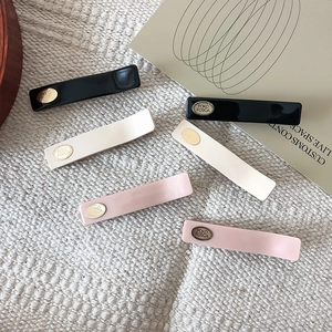 Flat lay of minimalist hair clips in black, beige, and pink colors on knit background