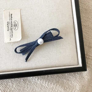 Macro detail van een marineblauwe denim strik haarclip met een witte parel kraal