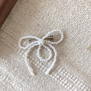 Exquisite Haarspange mit Perlenbesatz und silberner Entenschnabelklemme auf Textil
