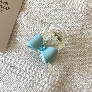 Détail d'une pince à cheveux avec nœud bleu et pierre précieuse sur tissu tricoté