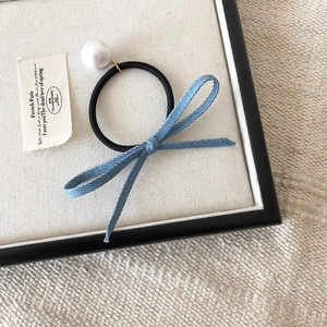 Detailopname van een blauwe denim haarelastiek met grote witte parel op vintage basis