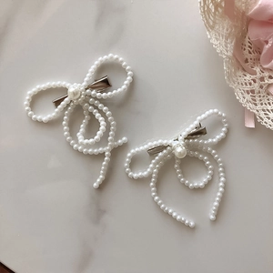 Exquisite Haarspangen mit Perlenbesatz in Schleifenform für Damen auf Marmor