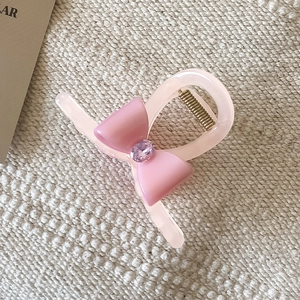 Détail de la pince à cheveux nœud rose avec gemme violette et ressort doré