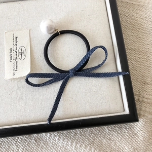 Detailopname van blauwe denim strik haarelastiek met grote witte parel op een wit dienblad