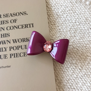Détail d'une pince à cheveux nœud violette avec un cristal rose facetté au centre