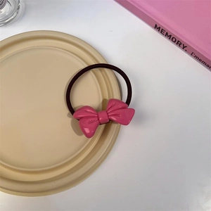 Élastique à cheveux avec nœud rose brillant et bande marron sur plateau décoratif