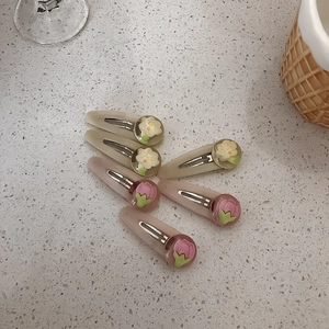Dettaglio di fermagli per capelli a fiori in resina color beige e rosa opaco