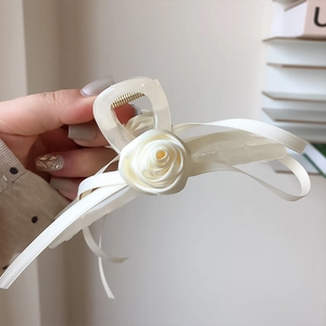 Détail d'une pince à cheveux crème avec rose en soie et nœud ruban à la main