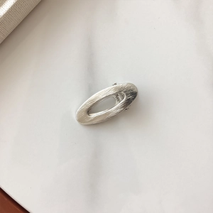 Minimalistische silberne ovale Haarspange mit gebürsteter Metallstruktur auf Weiß