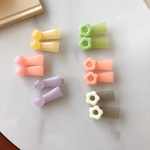 Floral and spherical resin hair clips in vibrant colors on a white marble surface
