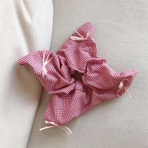 Red gingham scrunchie with pink bows on a textured background for women