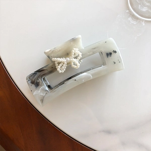 Dettaglio della molletta per capelli marmorizzata con fiocco decorativo di perle