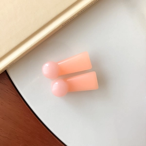 Detail of two peach pink resin hair clips with rounded ends in a sweet minimalist style