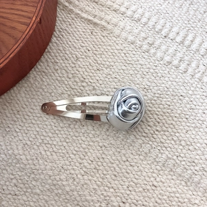 Detail shot of a silver rose flower hair clip with a brushed metal texture finish