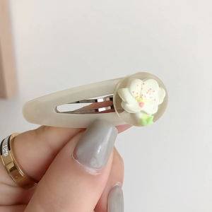 Dettaglio del fermaglio per capelli a fiori bianco crema con accenti rosa in resina