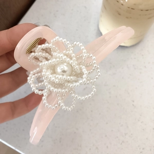 Pinza per capelli in resina rosa con fiori di perle su sfondo di marmo raffinato
