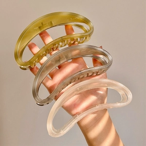 Detailed view of large crescent hair claws in olive green, grey, and cream finishes