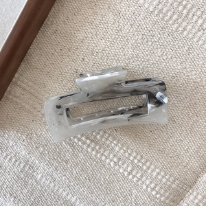Minimalist marble ink pattern acetate hair claw clip on a textured cream fabric background