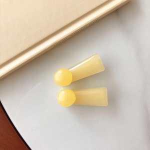 Detail of cream yellow flower hair clips with smooth resin texture on marble surface