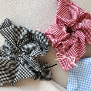 Detail of plaid scrunchies with ribbon bows in black, red, and blue cotton fabric