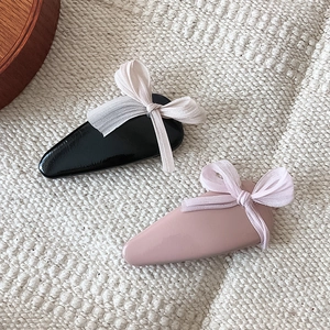 Detail of sweet bow hair clips in black and pink on a warm knit texture backdrop