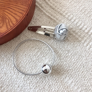 Silver metallic rose hair clip and elastic hair tie set on a soft knit background