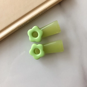 Detail of two light green floral hair clips with semi-transparent finish on a book