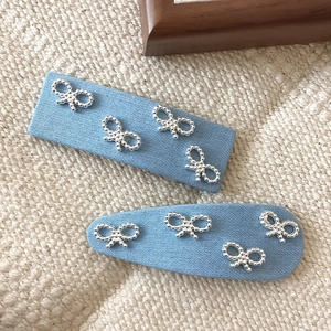 Detailed shot of light blue denim BB clips with silver metal bead bow embellishments