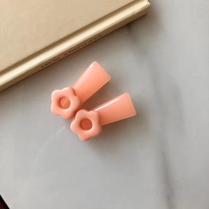 Close-up of pink flower hair clips on a marble surface with minimalist aesthetic style