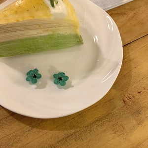 Vue macro détaillée d'une boucle d'oreille fleur en résine verte avec un centre en gemme