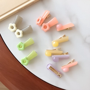 Pastel flower-shaped hair clips in candy colors arranged on a marble surface