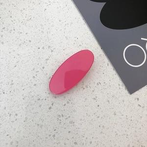 Detailed view of rose pink oval resin hair clip on a white textured stone surface