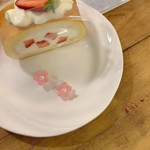 Boucles d'oreilles fleurs roses avec perle centrale sur assiette blanche et dessert